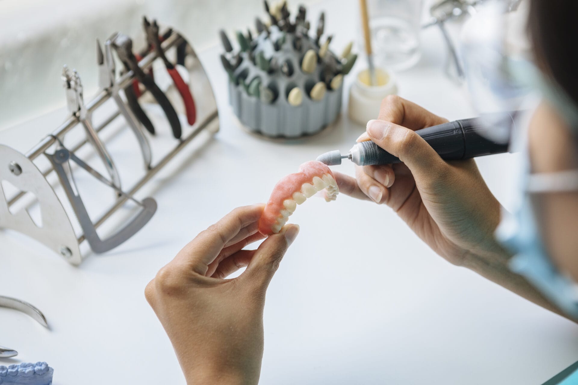 A closeup shot of hands working on a denture with a tool
